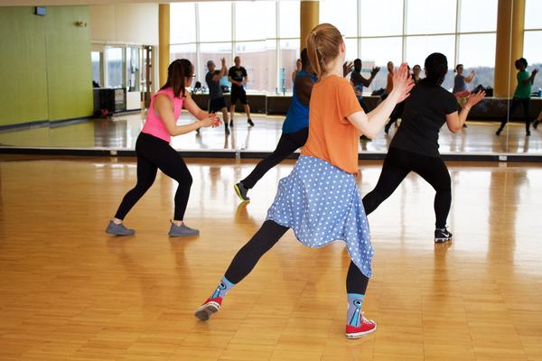 Photo of women dressed in gym-wear dancing in a fitness studio