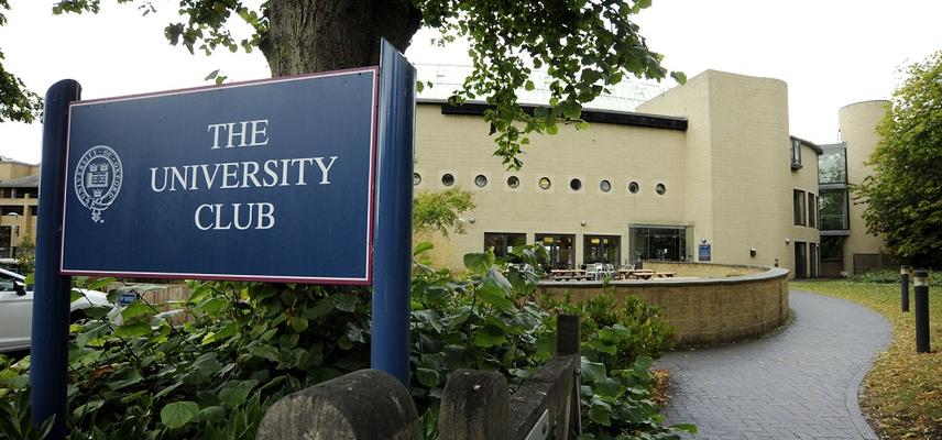 Photo of a blue sign reading 'The University Club' in white text, outside the front of the Club