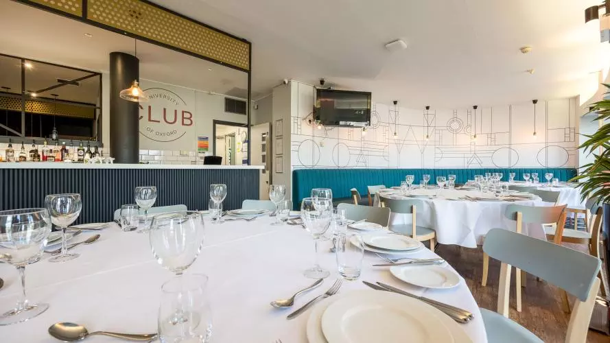 Round tables laid out for dining with plates, glasses and cutlery in the University Club Bar and Terrace area.